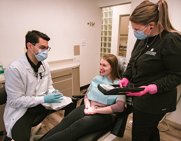 Doctor-with-female-patient A woman patient is sitting comfortably in the dental chair and listening to the dentists