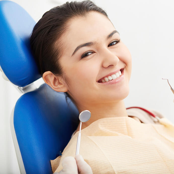 A young female patient sitting in a dental chair showing her brilliant smile