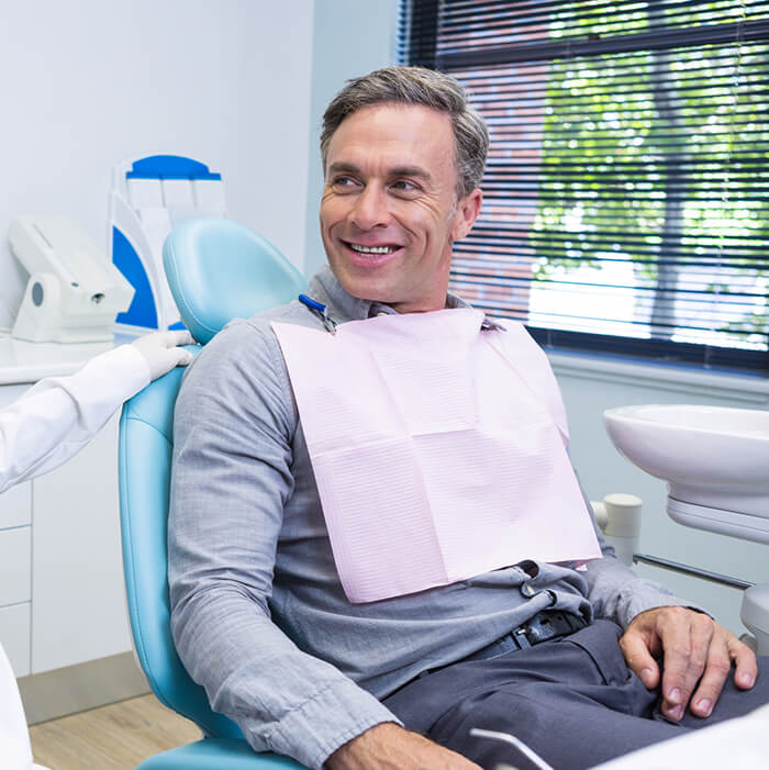 Get to know more about our dental bridge procedure A man sitting in a dental chair smiling
