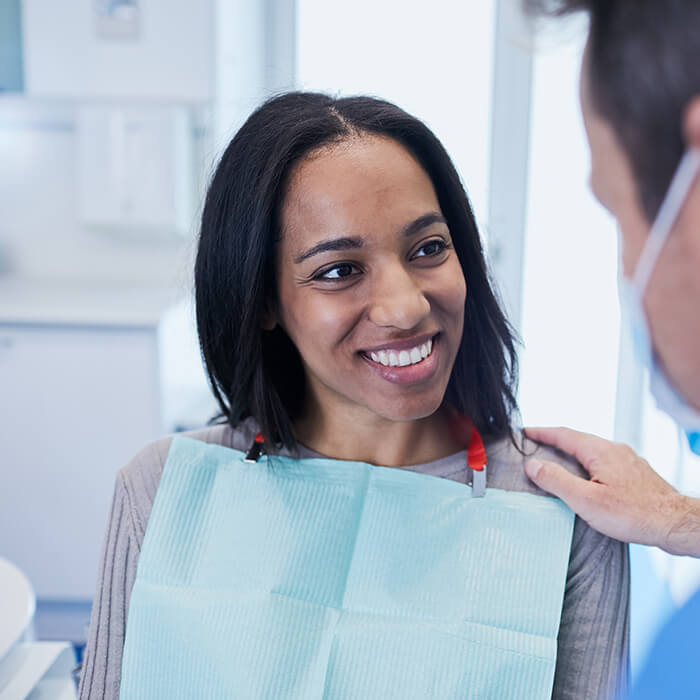 Proper dental care is the first step to a healthier smile. A female patient smiling and conversing with a team member