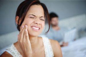 A female is holding her cheek to ease her toothache pain