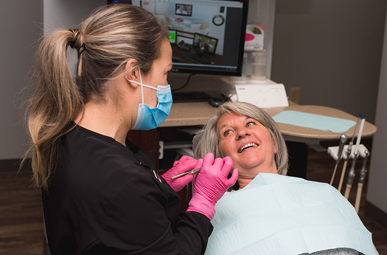 A woman patient is sitting in the dental chair and listening to the dentists